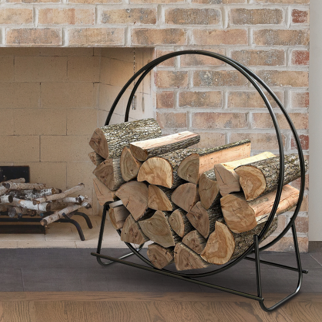 A stylish black log loop rack placed near a cozy indoor fireplace with a brick background.
